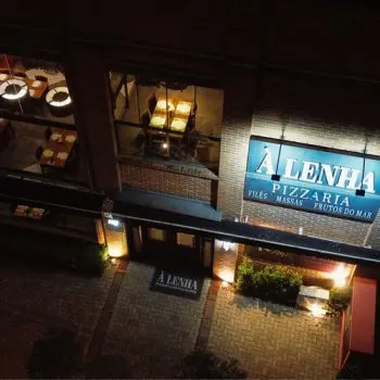 Fachada iluminada da pizzaria À Lenha em Capão da Canoa.